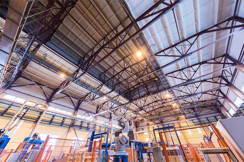 Interior of a factory workshop featuring industrial machines, high ceilings, and structural beams, highlighting a modern production environment.